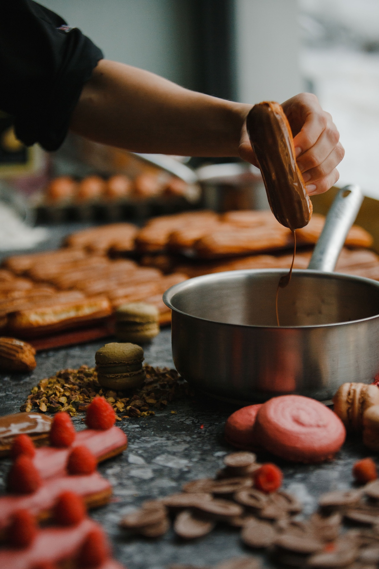 Chocolate éclair being dipped in glaze at Mulberry