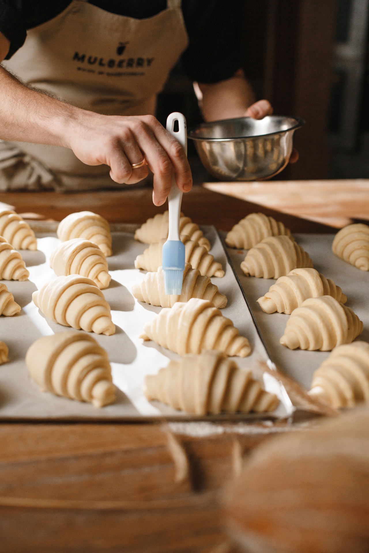 Brushing freshly shaped croissants at Mulberry